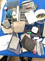 Assorted toiletry items, organizer, pouches, combs, clock movement, foot warmers on blue surface