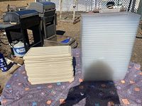 Stack of beige plastic lids next to stack of translucent storage bins outdoors