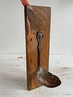 Front view showing silver-plated spoon attached to wood board