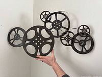 Full view of welded metal movie reel wall art held against wall