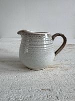 Front profile of stoneware creamer showing glaze, handle and spout