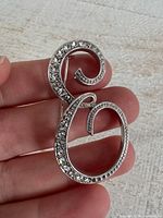 Front view showing silver-tone letter E brooch with rhinestones