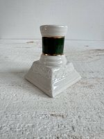Front view of white ceramic candlestick with green band and gold trim