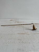Full view of brass candle snuffer showing twisted handle and star base