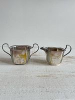 Front view of creamer and sugar bowl showing engraving and overall design