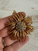 Front view of gold-tone flower brooch showing rhinestone cluster