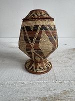 Front view of woven pedestal basket with lid