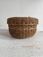 Side view of round woven lidded basket showing overall form and weave