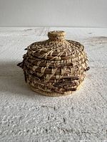 Front view of round pine needle basket with lid on
