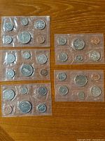 Five Royal Canadian Mint proof-like coin sets in sealed sleeves on wooden surface