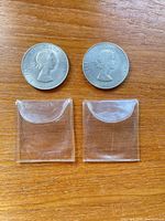 Obverse view of two 1965 Churchill crown coins with plastic sleeves below