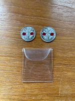 Front view of both colourized poppy coins with empty plastic sleeve