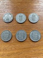Front view of six shilling coins on wood surface