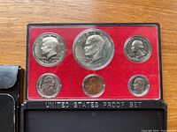 Obverse view of six coins sealed in red felt holder within plastic case
