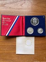 Set open showing three coins in blue flocked case and outer sleeve