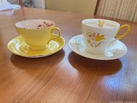 Both teacup and saucer sets side by side on table