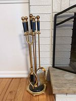 Full view of stand holding all four brass fireplace tools