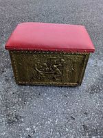 Front view showing red padded top, embossed brass panel, overall form