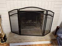 Front view of black three-panel fireplace screen on hearth