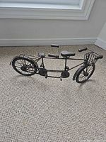 Left side view of metal tandem bicycle showing dual seats, handlebars and chainsets