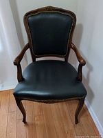 Front view of armchair showing leather upholstery, nailhead trim, carved crest