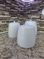 three white glossy ceramic canisters on countertop showing finish and relative sizes