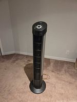 Full view of black Seville Classics tower fan standing on carpeted floor