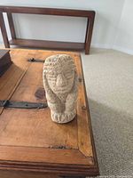 Front view of beige stone carved figurine on wooden table