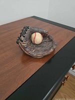 Front view of glove figurine holding baseball