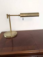 Front view of brass table lamp showing cylindrical shade, base and arm