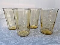 Four amber depression glass juice tumblers grouped on table