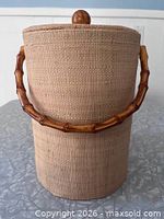 Front view of grass cloth ice bucket with bamboo handle and wood knob lid