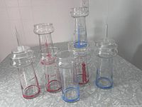 Six CN Tower-shaped glasses, two with plastic spires, red and blue printing visible