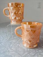 Two Fire-King Kimberly peach lustre diamond mugs overview