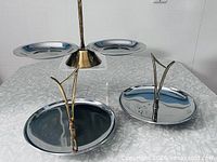 All three Kromex chrome trays displayed: two handled trays and one pedestal three-arm tray