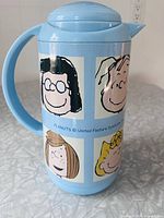 Front view showing Peanuts character portraits on light blue flask