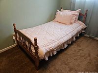 Full view of wooden single bed frame with mattress against wall