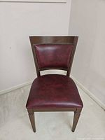 Front view of wood chair showing burgundy upholstered seat and back with nailhead trim