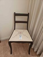 Front view of dark wood chair with embroidered seat