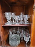 Cabinet view showing two shelves of crystal stemware and stacked plates