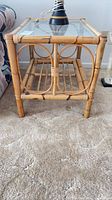 Front view of bamboo and rattan end table with glass top and shelf