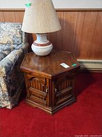 Front view of hexagonal wooden end table next to sofa, showing doors and hardware