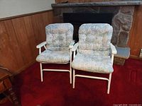 both white metal folding chairs with cushions in front of fireplace
