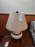 Full view of first lamp showing ceramic base, pleated shade, cord