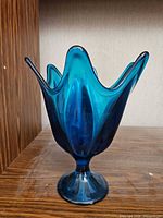 Front view of blue art glass pedestal vase