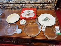 All items displayed on table: glass pie plates, enamel pie plate, boxed Nikko tier tray, Nikko serving plate, Villeroy & Boch trinket box, aluminum coaster, glass platter partially visible