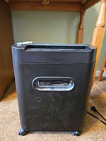 Front view of black paper shredder showing clear window and casters