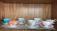 Full shelf view showing all eight teacup and saucer sets