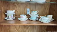Shelf view showing six teacup and saucer sets