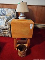 front view of stacked wooden TV tables on stand with lamp and sofa nearby